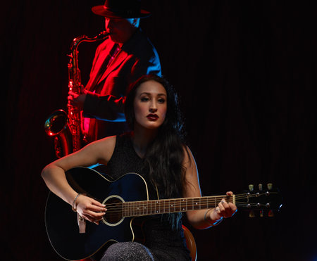 Beautiful woman plays a guitar, smoky stage on backgroundの写真素材