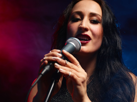 Beautiful woman sings, smoky stage on backgroundの写真素材
