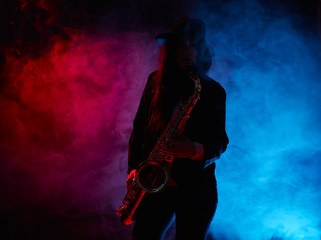 Saxophonist, beautiful young woman, smoky stage on backgroundの写真素材