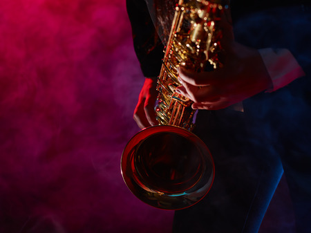Saxophonist, beautiful young woman, smoky stage on backgroundの写真素材