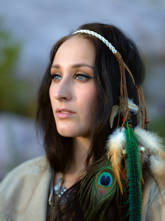 Attractive young woman wearing a feather headpiece, summer eveningの写真素材