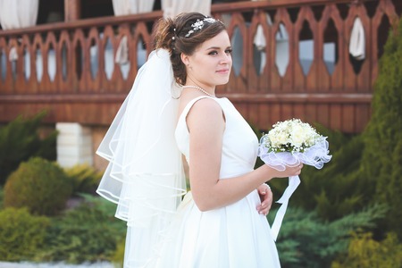 beautiful bride in a white lush dress walks outdoorsの写真素材
