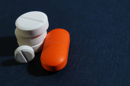 Colorful pills closeup on a dark blue background, concept of health and medicine, space for text