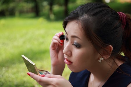 girl looks in round mirror against summer green parkの写真素材