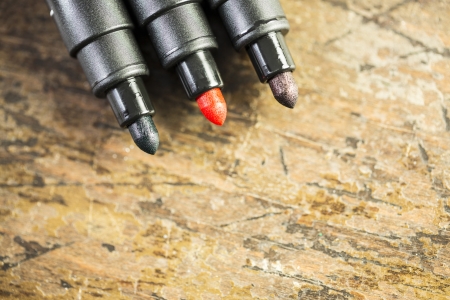 three markers on the old table - red, blue, blackの写真素材