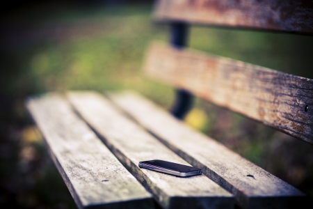 Someone forgot cell phone on a bench in the parkの写真素材