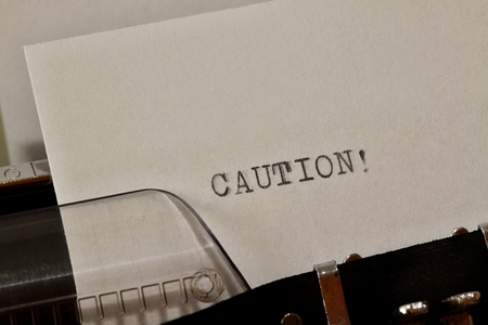 Caution text on white paper typed on old typewriterの写真素材