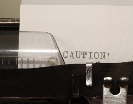 Caution text on white paper typed on old typewriterの写真素材