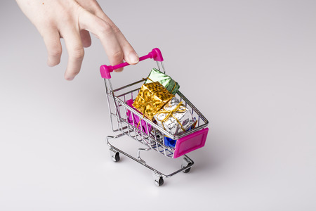 beautiful pink shopping cart in woman hand with white background and blue gift - shopping conceptの写真素材