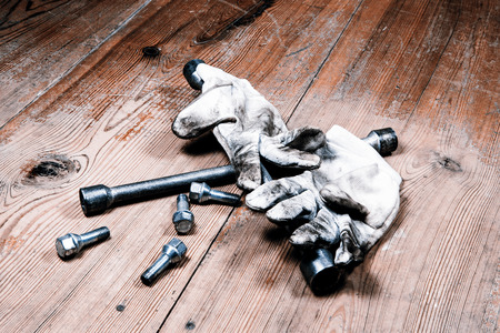 automotive tool - screwdriver for changing tires and dirty gloves on wooden floorの写真素材