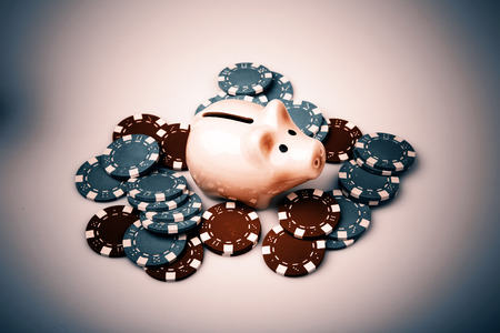 cute pig money box with casino chips over whiteの写真素材