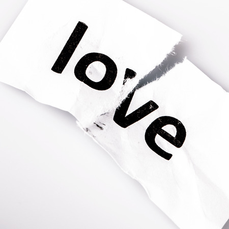 "Love" word written on torn paper on whiteの写真素材