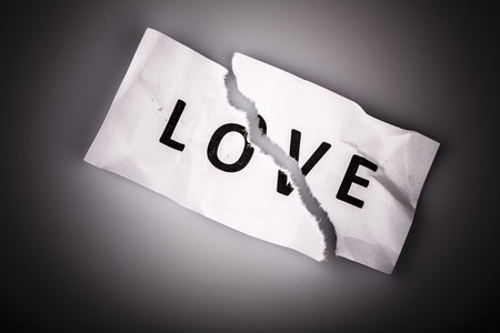 "Love" word written on torn paper on whiteの写真素材