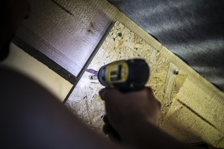 Black and yellow cordless drill in man hand - working with woodの写真素材