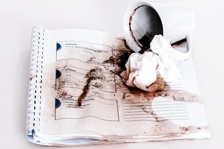 spilled coffee form cup on the notebookの写真素材