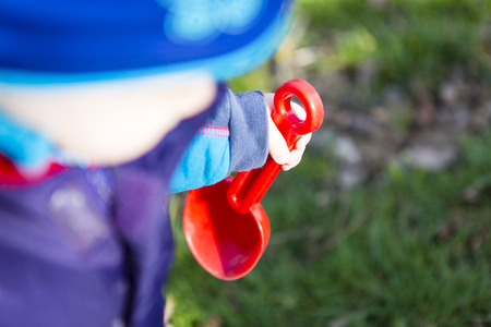 Child playing with red shovelの写真素材
