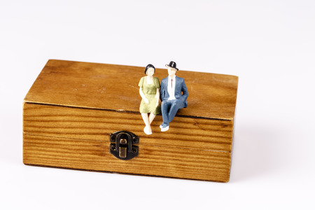 toy models of old couple sitting on wooden box on whiteの写真素材