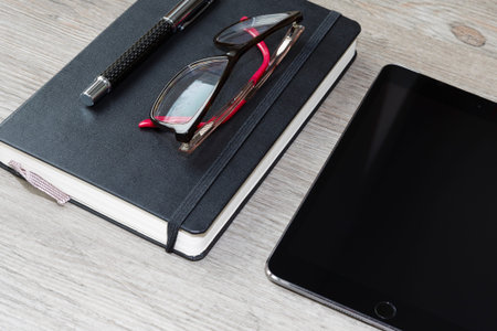 black calendar or diary with pen, glasses, smarthphone and tablet on wooden table, cellphone, floor