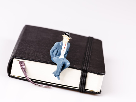 model of man sitting on organizer or planner, diary on whiteの写真素材