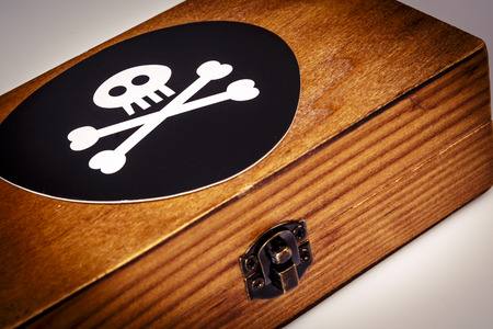 old wooden box with pirate symbol on white - skull and bones on blackの写真素材