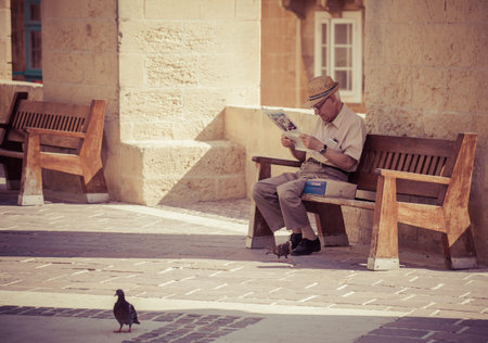 VALLETTA, MALTA - JULY 17: Senior reading newspaper in Valletta on July 17, 2015 in Vallettaのeditorial素材
