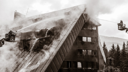 JASNA, SLOVAKIA - OCTOBER 6: Fireman with hose on ladder in front of hotel Junior Jasna  in Low Tatras mountains on October 6, 2015 in Jasnaのeditorial素材
