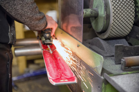 Person grinding skis. Hand of a worker maintaining skis in a grinding machine