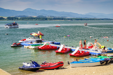 LiPTOVSKY TRNOVEC, SLOVAKIA - AUGUST 2: People relaxing and sunbathing on shore of water reservoir Liptovska Mara. Summer sports  at lake  on August 2, 2017 in Liptovsky Trnovecのeditorial素材