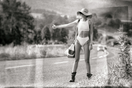 Hitchhiking young woman in bikini and sunhat on stopping the carの写真素材