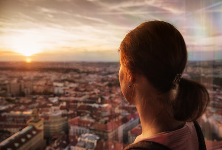 Woman watching on sunset over city Prague, Czech republicの写真素材