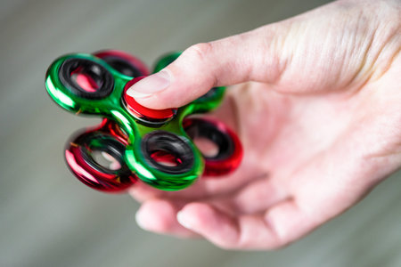 Detail of green fidget spinners in hand and red background