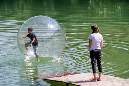 Young boy playing inside a floating water walking ball. Aquazorbing