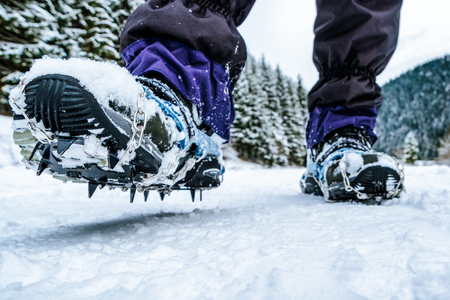 Crampons on hiking boots. Close up view on shoes on snowy pathの写真素材