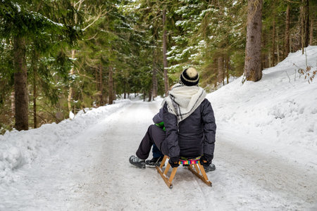 Mother and child riding a sled at winter forest