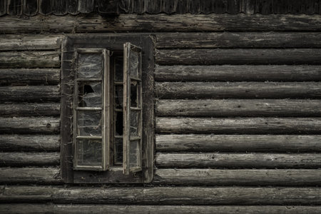 Open old window with broken glass in cottage with cobwebs