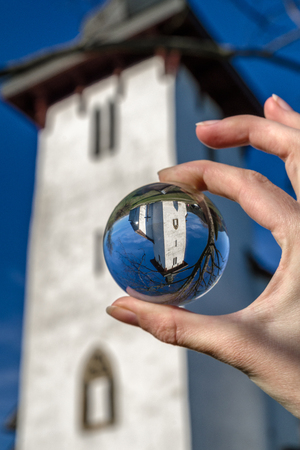 Reflection of church of St. Martin in village Martincek, Slovakia. Crystal lenball in handの写真素材
