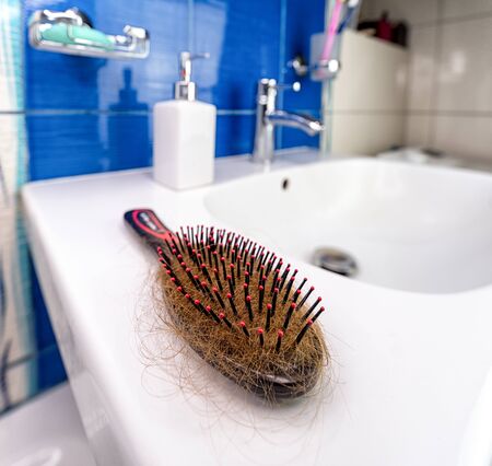 Hairbrush full of hair on the sink. Hair loss conceptの写真素材