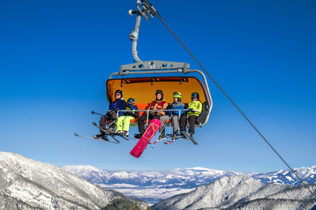 DEMANOVSKA DOLINA, SLOVAKIA - FEBRUARY 8: Skiers sitting on ski lift chair  in ski resort Jasna on...