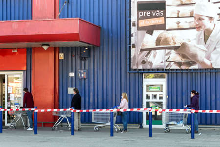 RUZOMBEROK, SLOVAKIA - APRIL 8: People with face masks standing in front of shop. Social distance due Coronavirus COVID-19のeditorial素材
