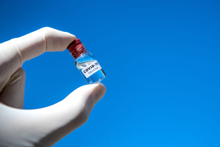 Coronavirus COVID-19 vaccine in hand with glowes on blue background