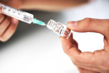 Corona virus COVID-19 vaccine and injection syringe in hand of doctor.の写真素材