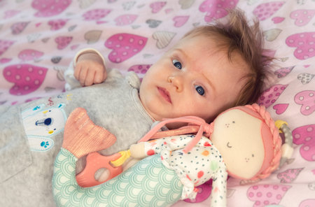 Small infant baby lying on back  with baby doll