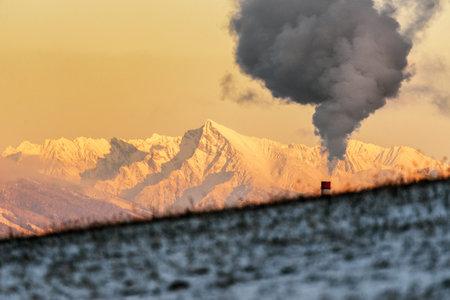 Smoke from chimney and hill at background. Snowy peak Krivan, Slovakia
