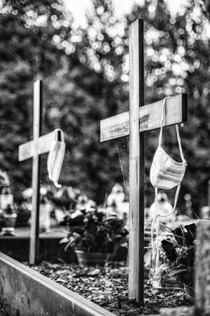 Protective mask on the cross of grave in cemetery. Victims of coronavirus Covid-19の写真素材