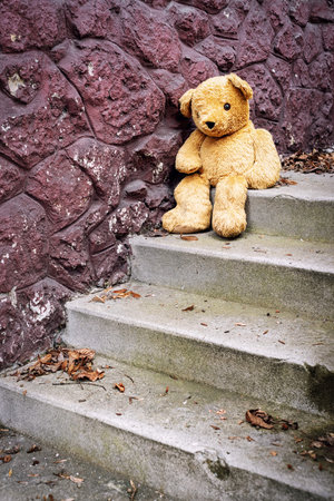 Brown teddy bear sitting on stairsの写真素材