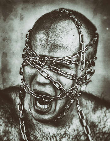 Psychotic look of screaming man with head in chains.の写真素材