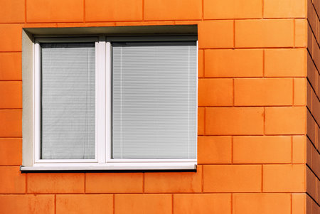 White blinds on closed window at house. Orange facade