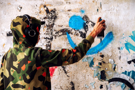 Boy in a hood spraying the wall. Graffiti concept.の写真素材