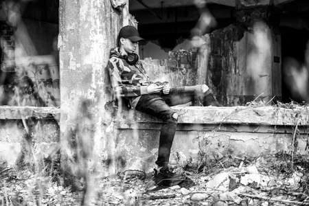 Young boy sitting on a crumbling building and using smarthphone.の写真素材