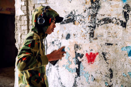 Young graffiti artist in hoodie spraying the wall. Street art conceptの写真素材